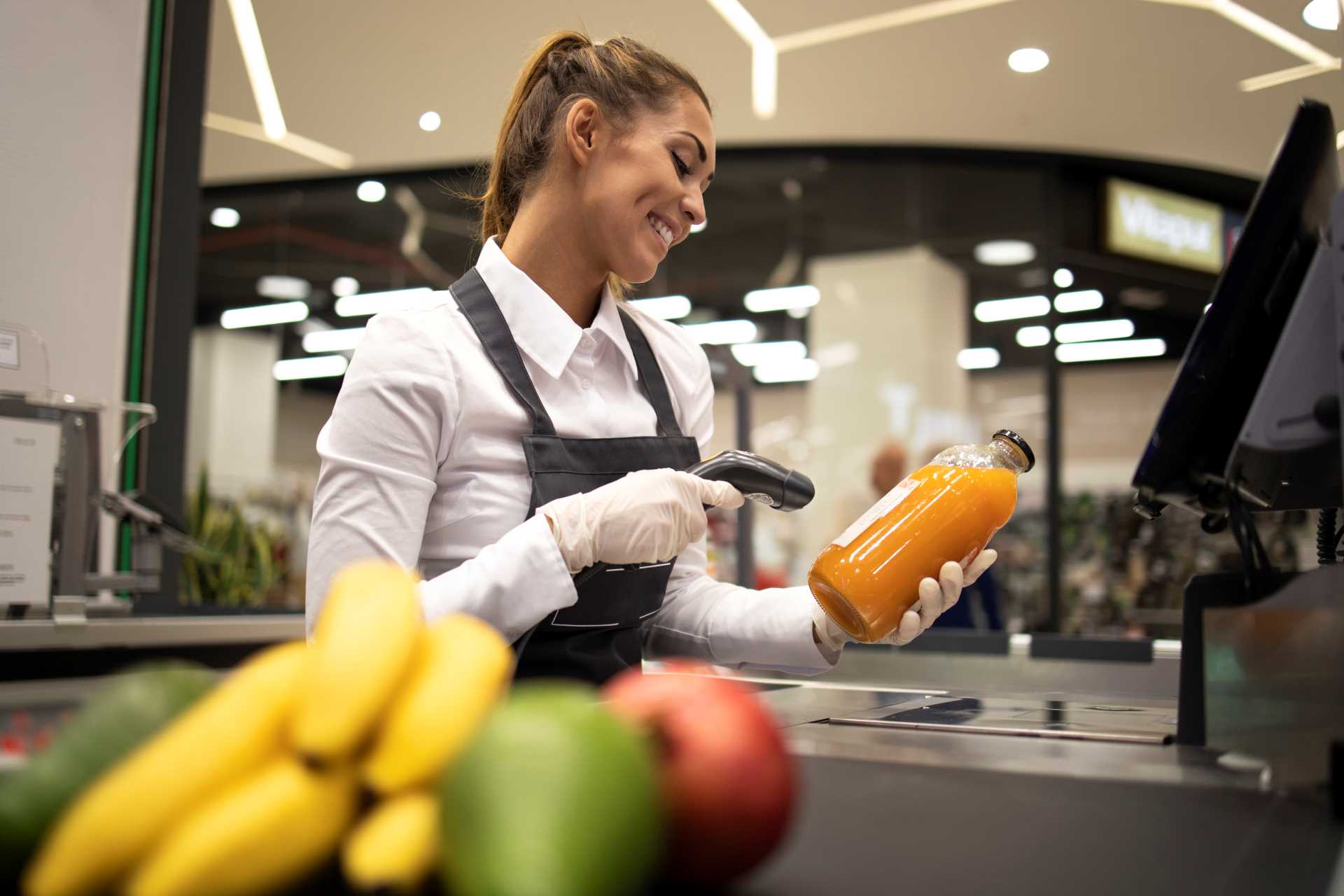 portraet der kassiererin im supermarkt der strichcode der produkte zum verkauf scannt
