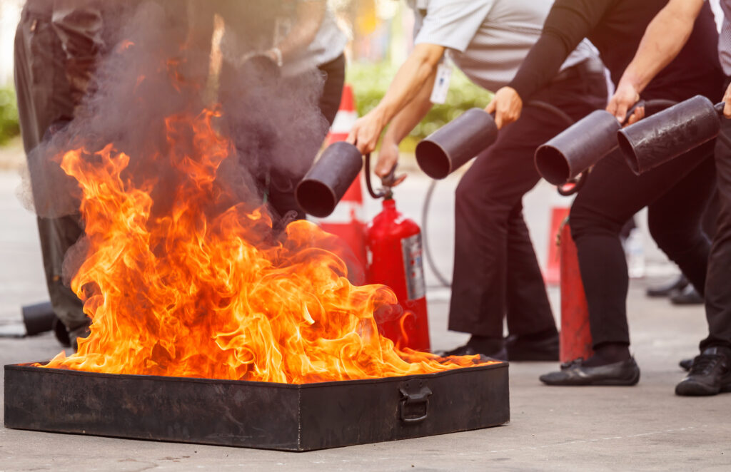 Personengruppe übt den Einsatz von Feuerlöschern bei einer Brandschutzschulung in Berlin